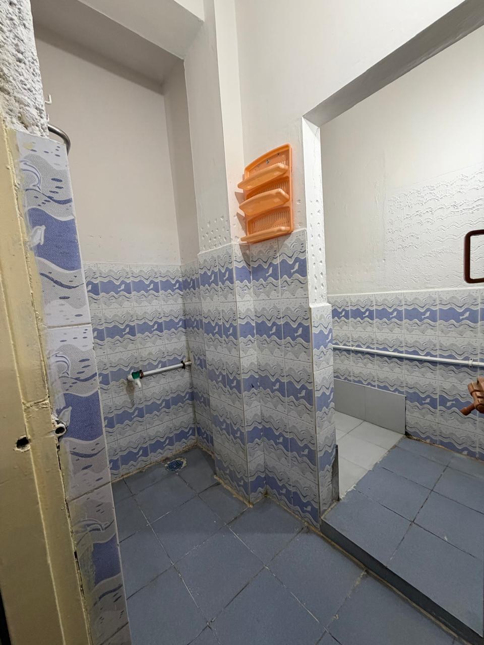 Clean tiled bathroom with shower area for four sharing residents